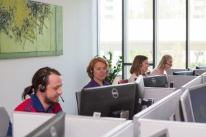 MitarbeiterInnen der telefonischen Gesundheitsberatung sitzen an PCs und beantworten Fragen